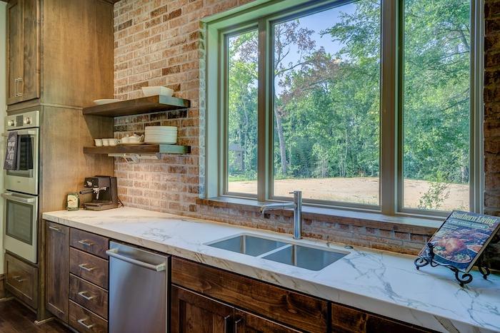 Trendový príklad kuchyne 2018 s tehlovou stenou a nízkou kuchynskou linkou s dreveným stĺpikom