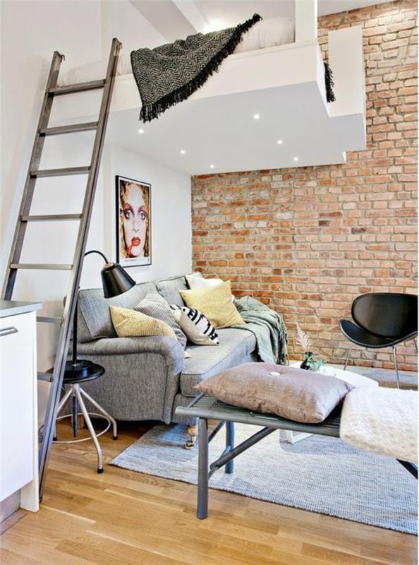 lägenhetinredning med en vit vägg och en brun tegelvägg, PVC -parkett i gult, fyrkantig matta i pastellgrått, säng nära taket, med vit kub, svart metallarmatur