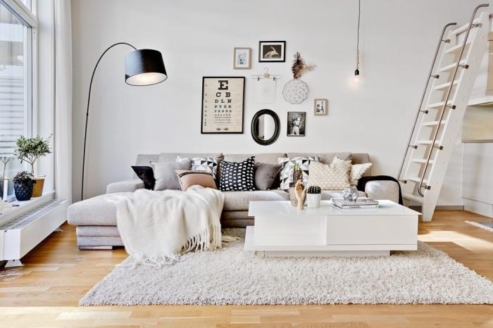Interiör i skandinavisk stil med kokande hygge deco, litet mysigt vardagsrum med stor mjuk soffa och ljus parkett som ger ljus
