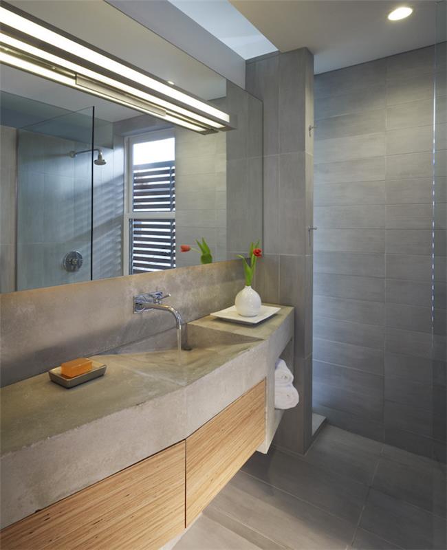kúpeľňová omietka s drezovou skrinkou z voskovaného betónu a dlažbou a stenami z cementovo šedej farby