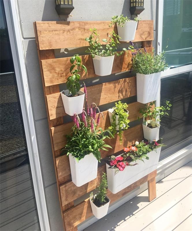 grön pallvägg enkel konstruktion träplankor hängande vita krukor blommande växter balkongdesign