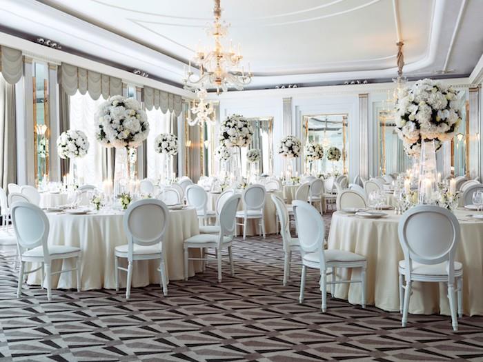 obrusy, stoličky a biele kvety na ozdobu elegantnej svadobnej miestnosti hnedým, čiernym a sivým kobercom