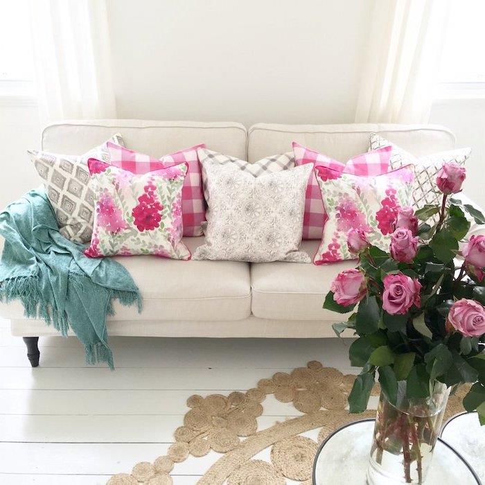 deco -trend, vardagsrum med vita väggar och golv, rosebukett i en glasvas, kuddar med rosa och vita blommönster