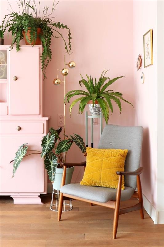 ženský interiérový dizajn v obývacej izbe s pastelovo ružovými stenami a drevenými podlahami, model kresla z tmavého dreva zdobený vankúšom v horčicovej farbe