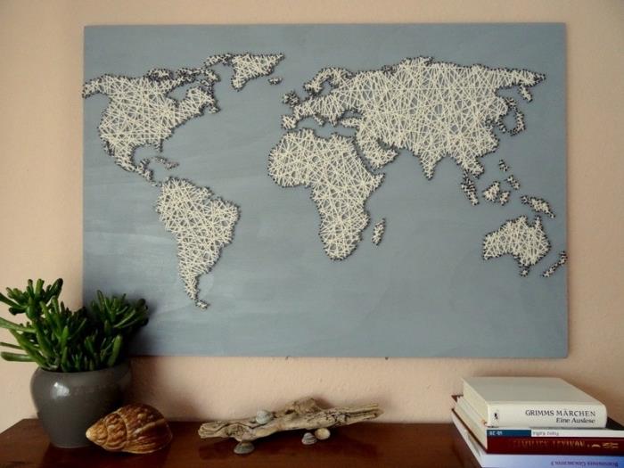 stor träbild målad i ljusblått med världskarta i vit tråd och konturer i svart tråd som ett enkelt DIY -objekt