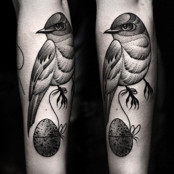 ägg som hänger på änden av en tråd och grafisk grå fågel på armen, djur tatuering design modell