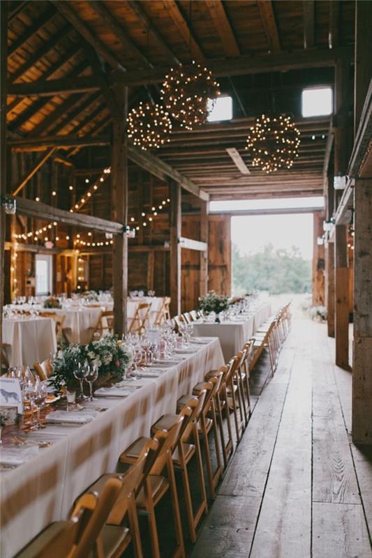 gule svetlých girlandov na ozdobu stropu starých zrekonštruovaných stodôl, drevené stoličky, stôl s bielym obrusom, kvetinová svadobná výzdoba do centra