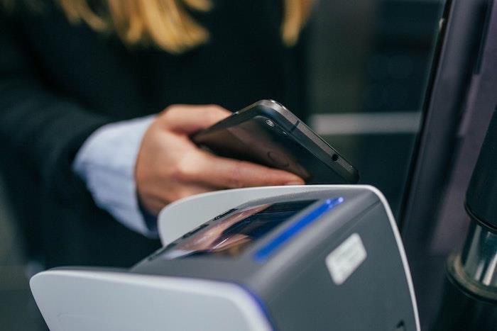 kvinna med mobiltelefon i handen som hänger och gör en telefonbetalning