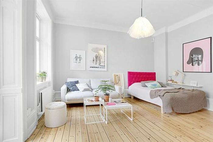 أرضية خشبية باللون البيج الفاتح ، داخل غرفة بجدران بيضاء ورمادية شاحبة ، سرير مع لوح وردي ساخن ، تصميم شقة ، أريكة بيضاء وطاولتي قهوة