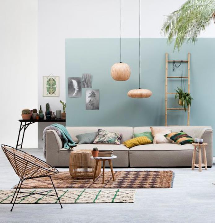 Nástenná časť prelakovaná Celadonovou modrou a ostatné biele steny, šedá pohovka, hnedý koberec, dizajnérska stolička, farebné ozdobné vankúše, dekoratívny bambusový rebrík