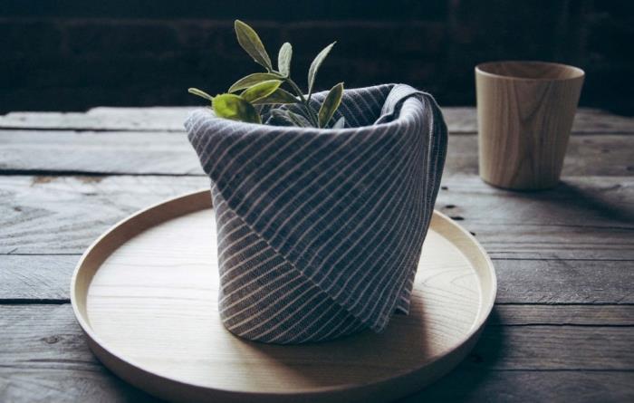 servett av grafiskt tyg vikt i en liten korg, enkelt och snabbt origami -påskvikningsmönster för att dekorera ett rustikt bord