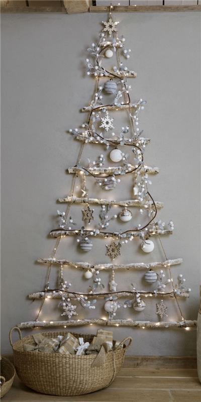 DIY väggdekoration för jul gjord med grenar och rep i form av ett minimalistiskt träd dekorerat med snöflingor