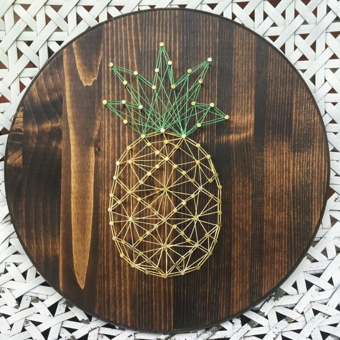 fint dekorativt föremål handgjort med en trådmall med gul och grön ananasdesign på en rund träskiva