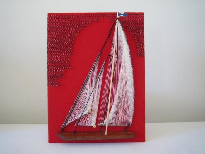 enkel handgjord objektmodell med röd svarta tavla med tråddekoration och vita och svarta båtdesignspikar