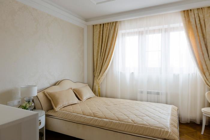 enkel inredning i sovrummet med gula gardiner och beige lädermöbler