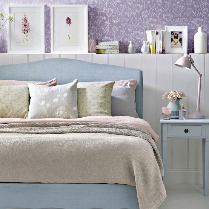 purpurová tapeta do spálne s bielymi kvetinovými vzormi, modrá posteľ, sivá, ružová a pastelovo zelená posteľná bielizeň, dekorácia do spálne, modrý nočný stolík
