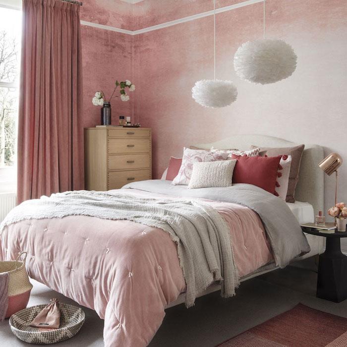 príklad ružovej a bielej tapety do spálne, ružovej, sivej a červenej posteľnej bielizne, dizajnových bielych závesných svetiel, drevenej komody