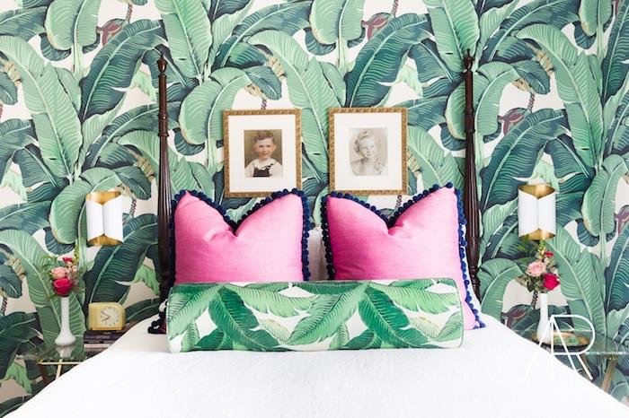 tapeta do spálne s tropickým vzorom, biela posteľná bielizeň, ružové vankúše, kytica čerstvých kvetov