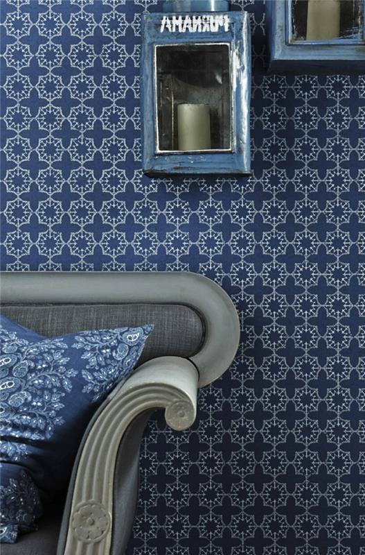 trompe l'oeil tapeter i blått och vitt, geometriska tapeter, vardagsrum med soffa i ljusgrått med dynor i blått och vitt, kinesisk stil, blå metallhyllor med stora grå ljus