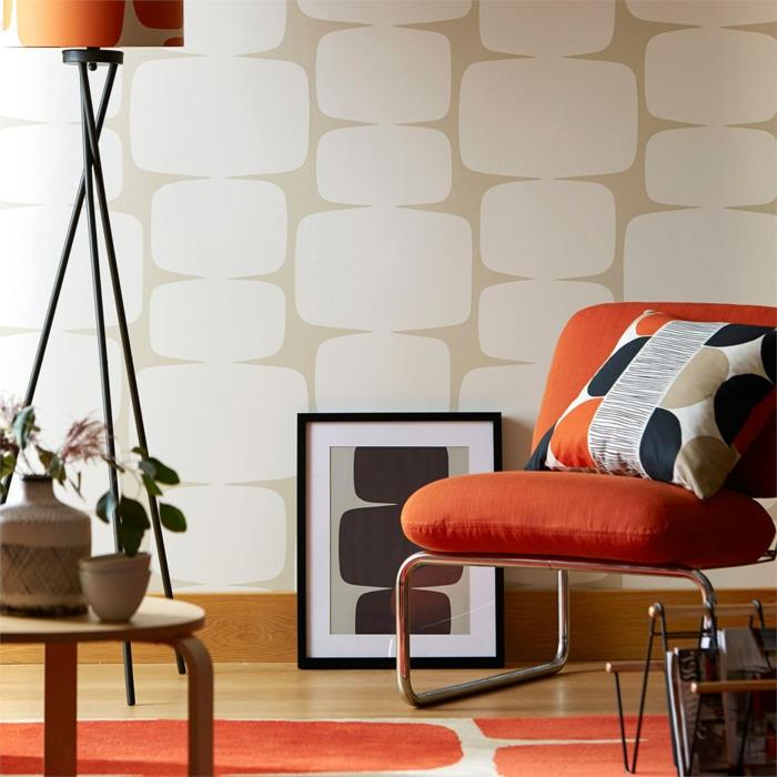 trompe l'oeil tapet i beige och vitt, golv i orange och vitt, fåtölj i vit metall, med två stora kuddar i orange, bord placerat på golvet i svart och vitt, svart ram, kudde på fåtöljen med runda geometriska former i orange, svart, vitt och beige