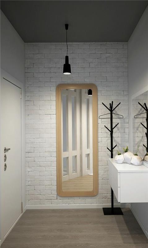 fiberduk tapeter i entrén till ett hus, vita tegelmönster, golvlampa i svart metall, svart metallskåp för hängande jackor, vitt hängande skåp, taupe golv, vit backspegel