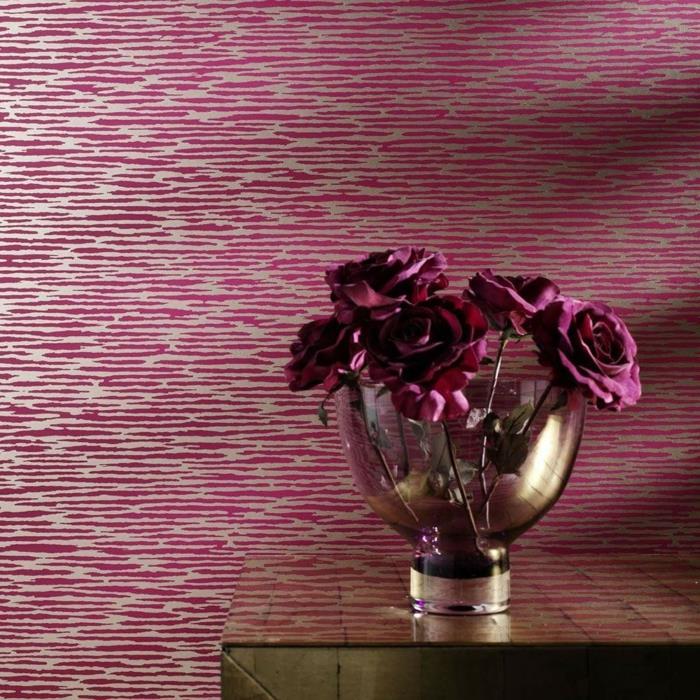 trompe l'oeil tapet i rosa och vitt, zebramönster, bord med blank skiva i guldfärg, transparent vit glasvas med vinröda rosor, raffinerad lyxig atmosfär
