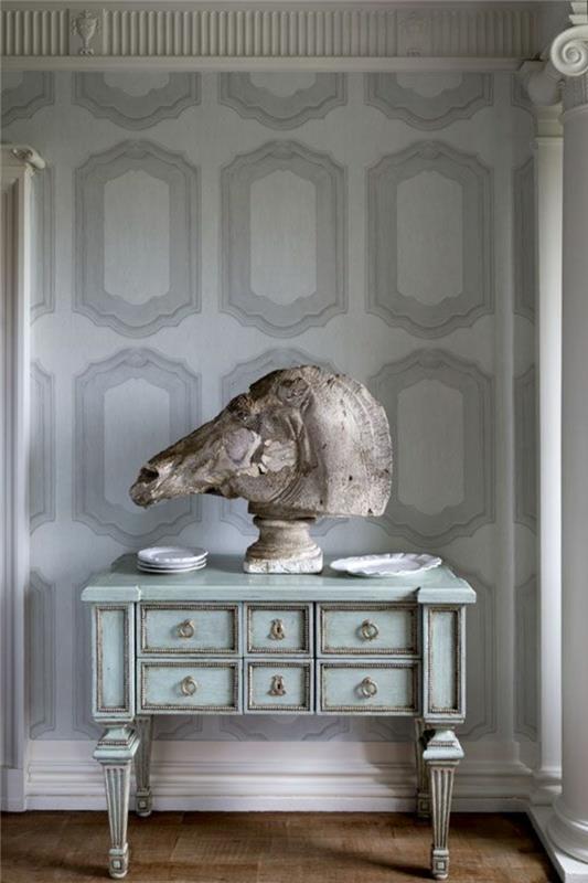tapeter i imiterad sten, lyxig entré, skåp i mintgrönt i shabby chic stil med ett stort hästhuvud på och vita porslinsfat, golv täckt med parkett i ljusbrunt