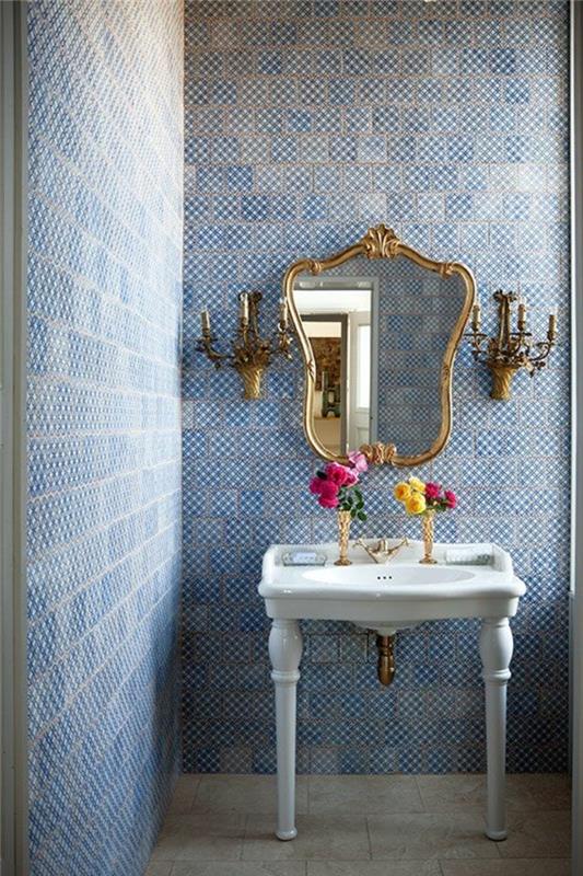 tapet trompe l'oeil i ett badrum i klassisk stil, med spegel i barockform med guldfärgad metallram, med två vägglampor i form av ljusstakar, i slottsstil, vägg i blått och vitt, mosaikeffekt den gamla