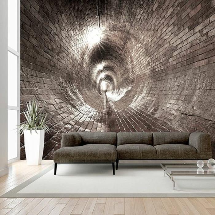 tapet trompe l'oeil i form av en spiral i tegelvägg i bronsfärg, vardagsrum med ljusgrå matta med kanter i mörkgrått, soffa i spenatgrönt, litet fyrkantigt soffbord i härdat glas, stor vit kruka med en växt grön palm
