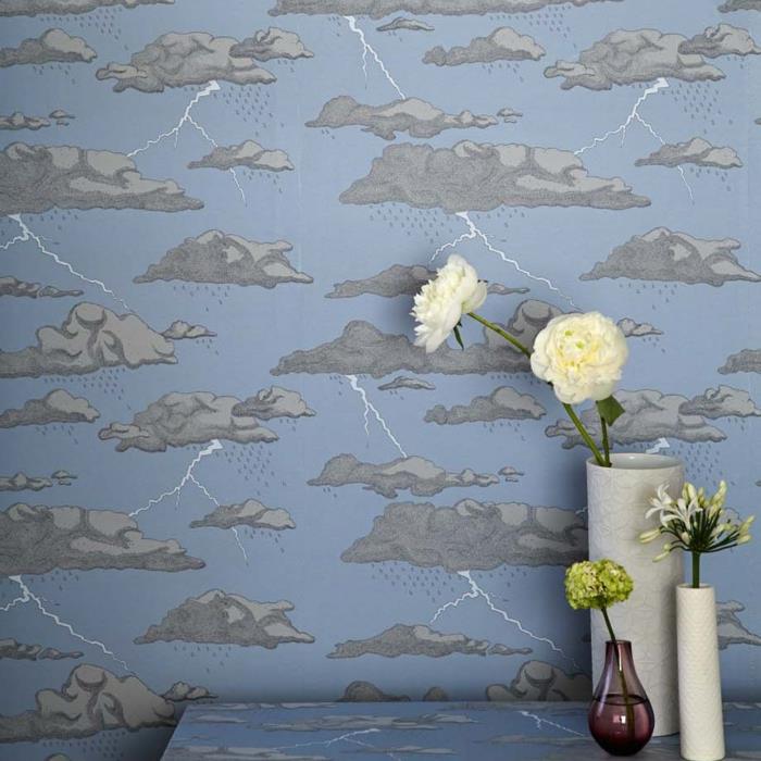 trompe l'oeil tapet i pastellblått med stormiga moln i ljus och mörkgrå, entrévägg i humoristisk stil, med entrébord med grumlig himmel, tre vaser med blommor, två vita vaser och en i rökt glasskugga rött