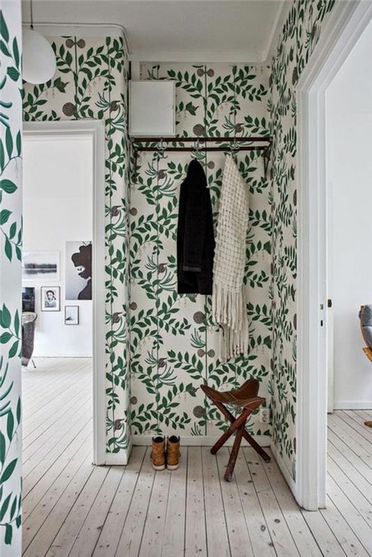 trompe l'oeil tapet i en entré, med krypande gröna växter, vitt tak, svart metall klädhängare