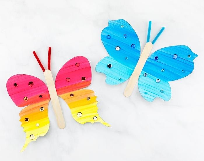 vyrobte motýľa s farebnými papierovými krídlami a telom z ľadovej tyčinky ozdobeným štrasom, anténami na čistenie potrubí