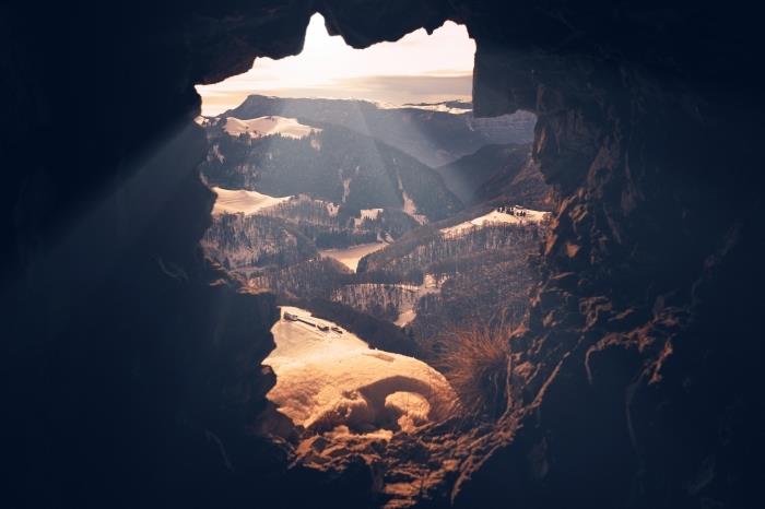 tmavý tapetový obraz s krajinou z vtáčej perspektívy, pohľad z jaskyne na hory a zelené polia