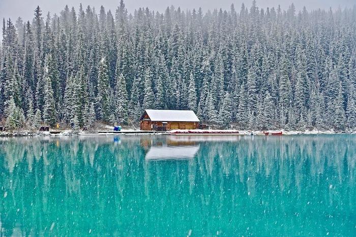 vinterlandskapstuga i bous vid kanten av en sjö omgiven av en snötäckt skog av granar, varför besöka Kanada