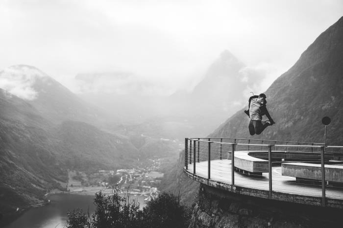 en man som hoppar på bakgrunden av majestätiska berg och en dal svartvitt porträtt man och natur