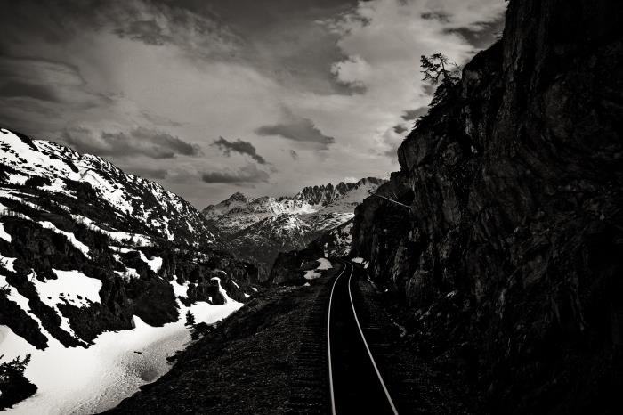 svartvitt fotografi av järnvägen i vinterberget som väver sig mellan klipporna