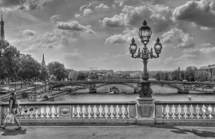 ett nostalgiskt svartvitt foto av Paris med utsikt över broarna under himlen prickade med moln