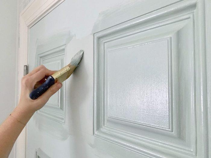 måla en dörr med en pensel och vit färg