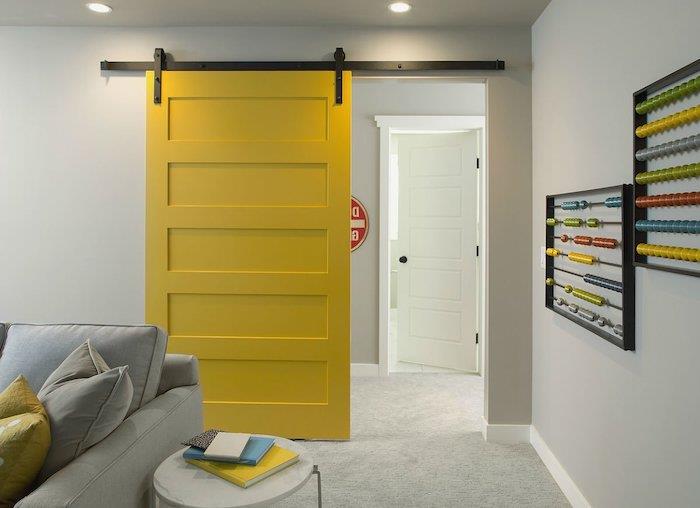 måla en skjutbar innerdörr i ljusgul färg i vardagsrummet med gula kuddar och grå soffor