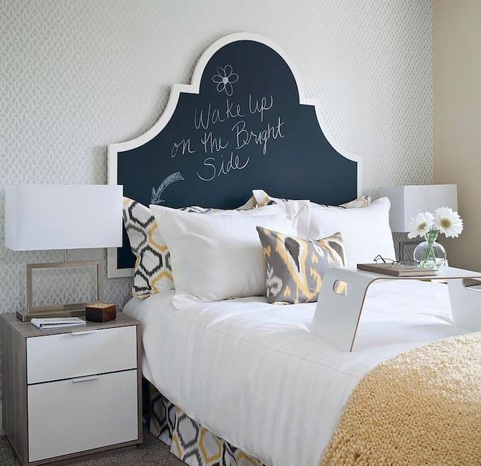 designer sänggavel i skifferfärg att skriva på den, gula, vita och gråa sängkläder, sängbord i trä