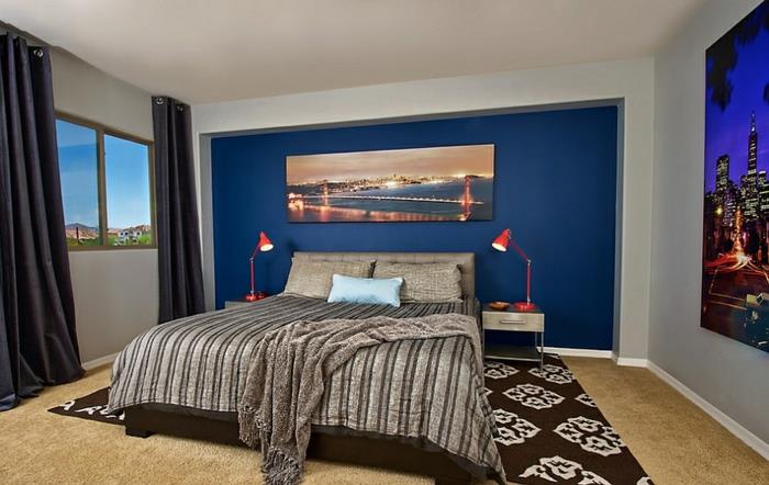 غرفة نوم حديثة للبالغين باللون الأزرق والرمادي الفاتح ، سجادة سوداء عتيقة ، طاولتان عائمتان بجانب السرير ، ملصقات جدارية ؛