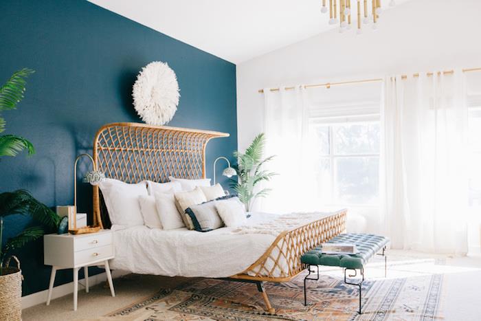 farba spálne pre dospelých, kačacia modrá s exotickou posteľou, biele prádlo, biely nočný stolík so zásuvkami, orientálny koberec, dizajnové závesné svetlo, zelené rastliny