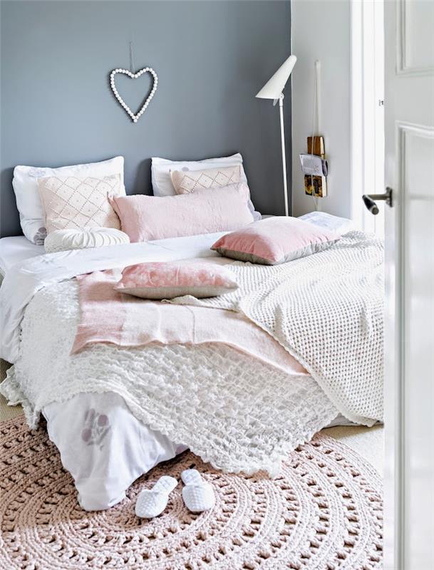 romantiskt sovrum, stor säng täckt med vit pläd och dekorativa kuddar i blekrosa