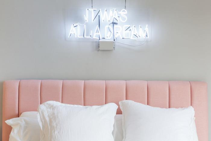 sovrumsdekoration med ljusgrå väggar, rosa sänggavel, lysande bokstäver ovanför sängen