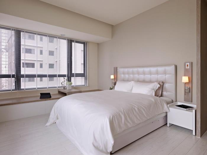 modernt designat sovrum med dubbelsäng med huvudknapp, minimalistisk inredning med säng och träbänk under fönstret