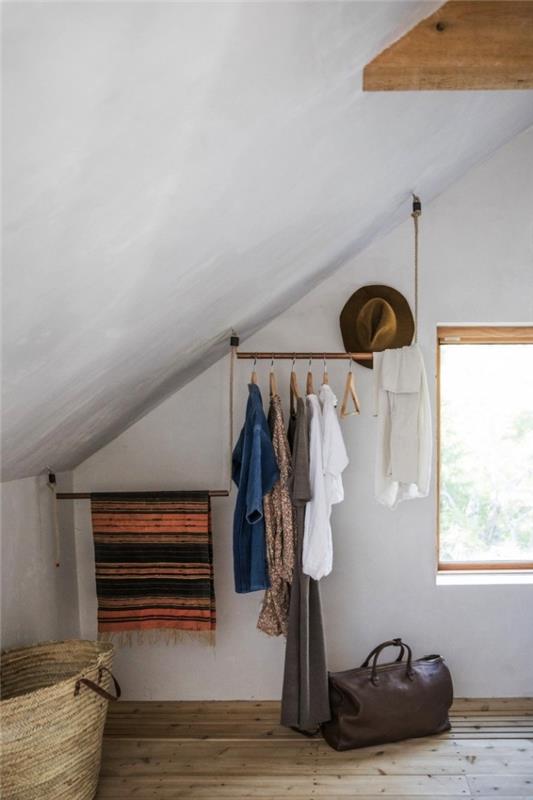 en sluttande garderob i ett hörn av vindsrummet med stänger fästa vid väggen