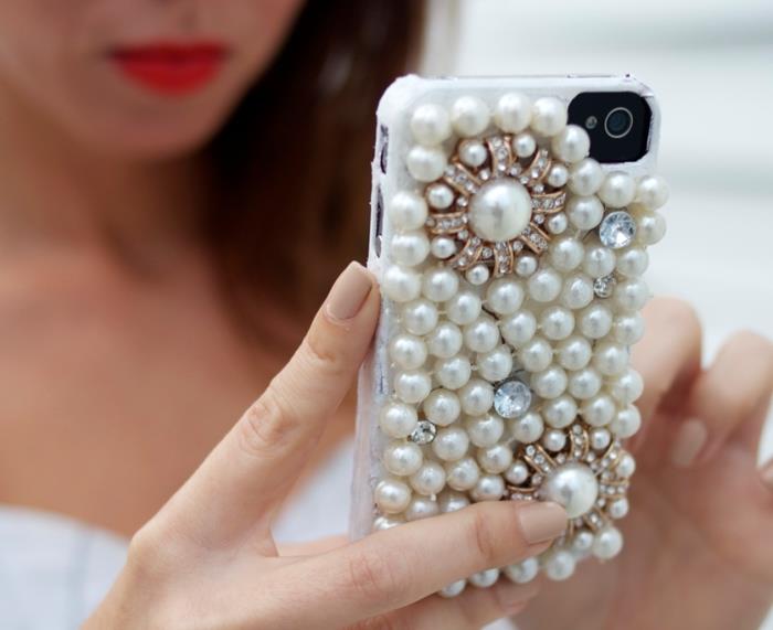 ženský šperk v tvare personalizovaného puzdra na iphone 7 s bielym obalom zdobeným bielymi perlami a rôznymi kryštálmi
