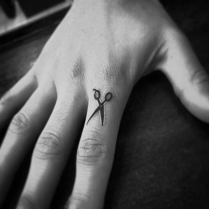 liten sax graverad med bläck på pekfingret, tatuering på handen i minimalistisk anda