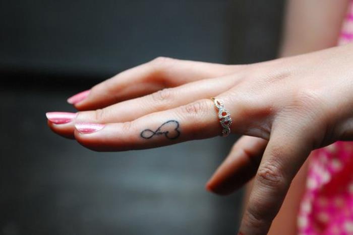 symbol nekonečna a malé srdce, jemné a rafinované tetovanie prstom