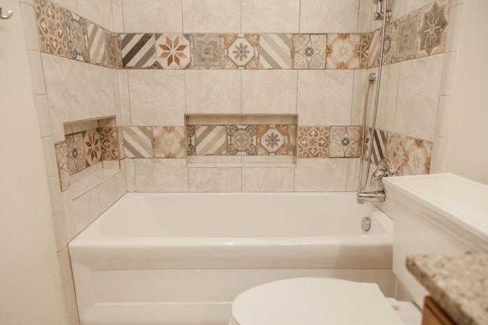 badrumsmodell med imiterade kakelväggar beige färgade cementplattor med litet badkar och dusch
